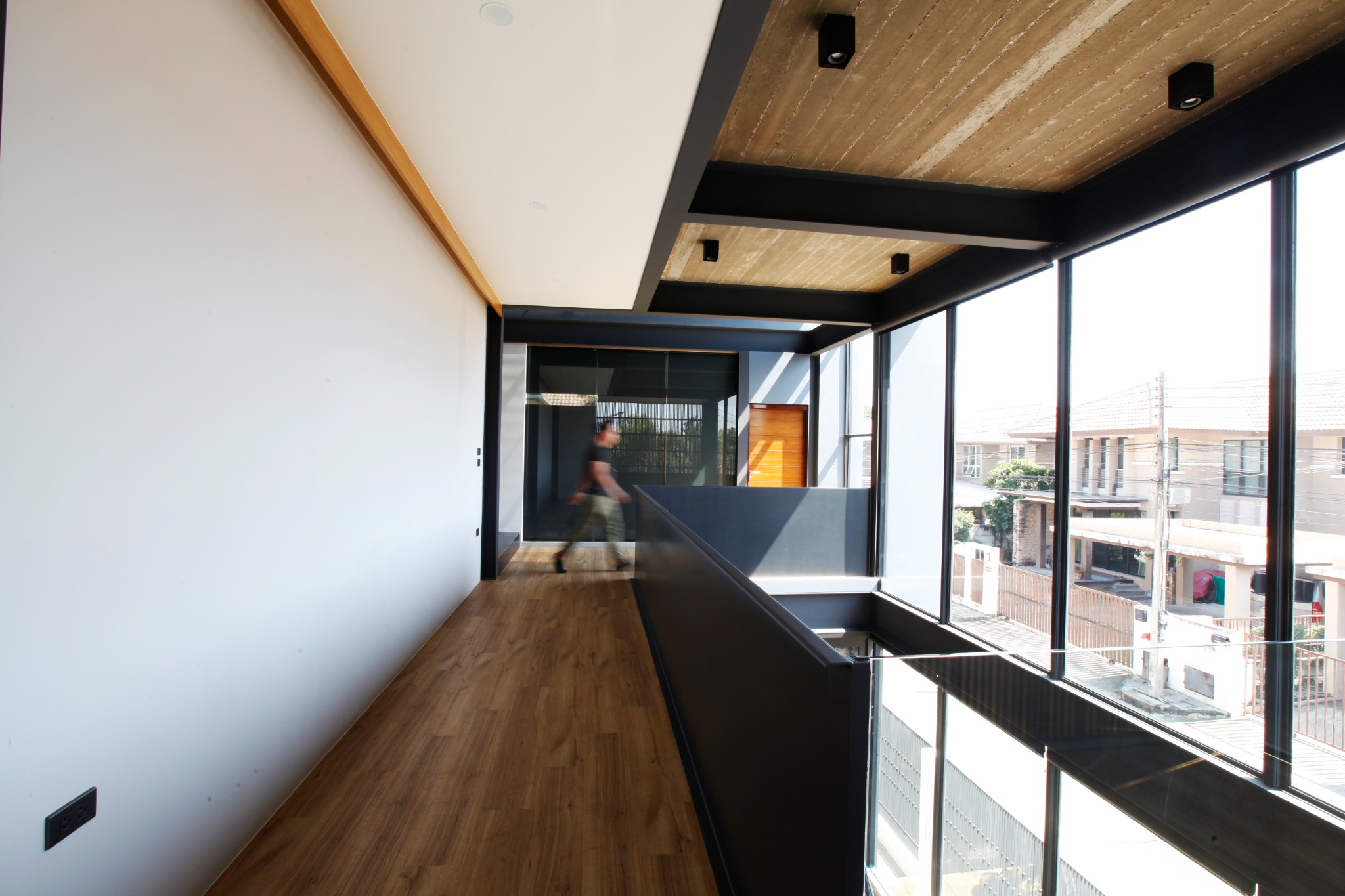 Upper-floor corridor overlooking the street through full-height glazing