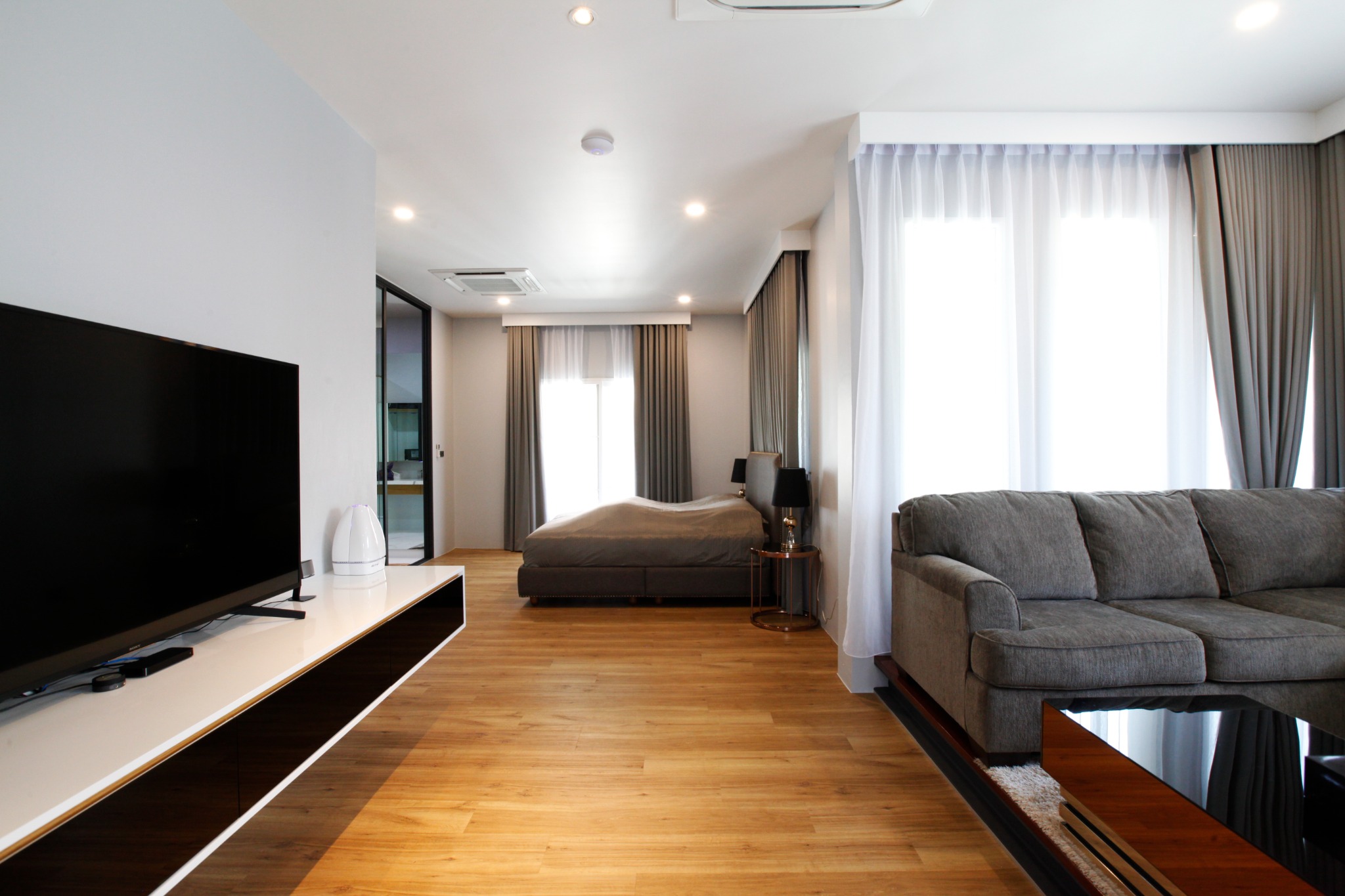 Living room with timber flooring, a television wall and grey sofas