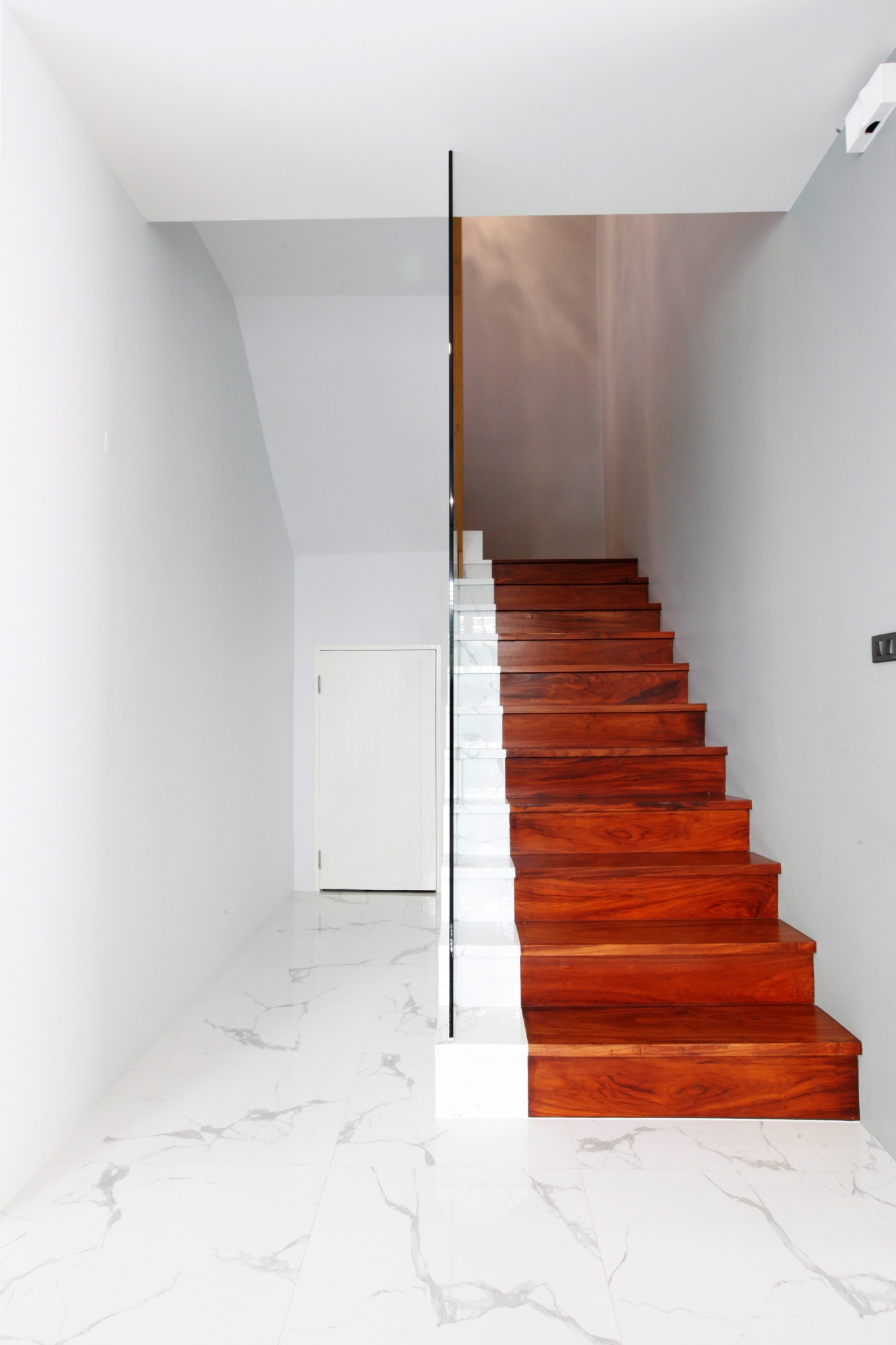 White stair hall with a timber staircase and marble floor
