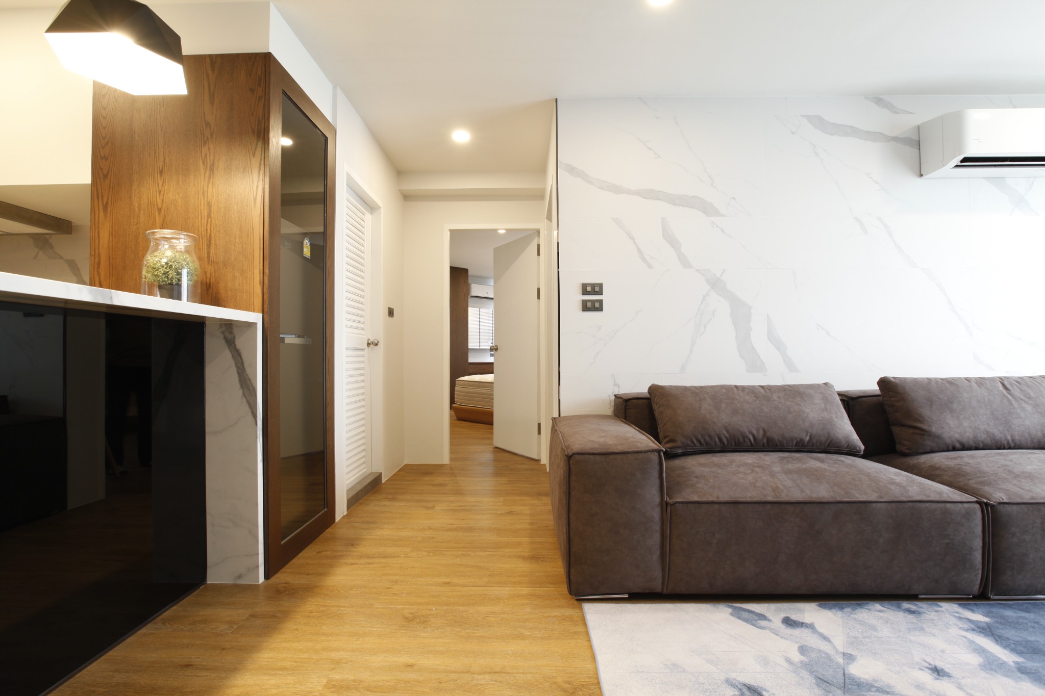 Living area with built-in black cabinetry, marble wall and grey sofa