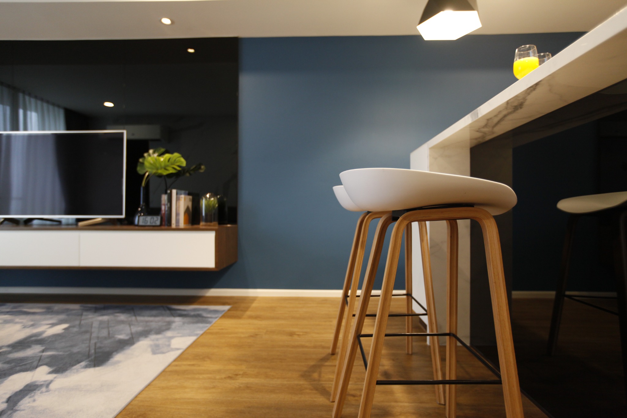 Breakfast bar detail with timber stools beside the blue living-room wall